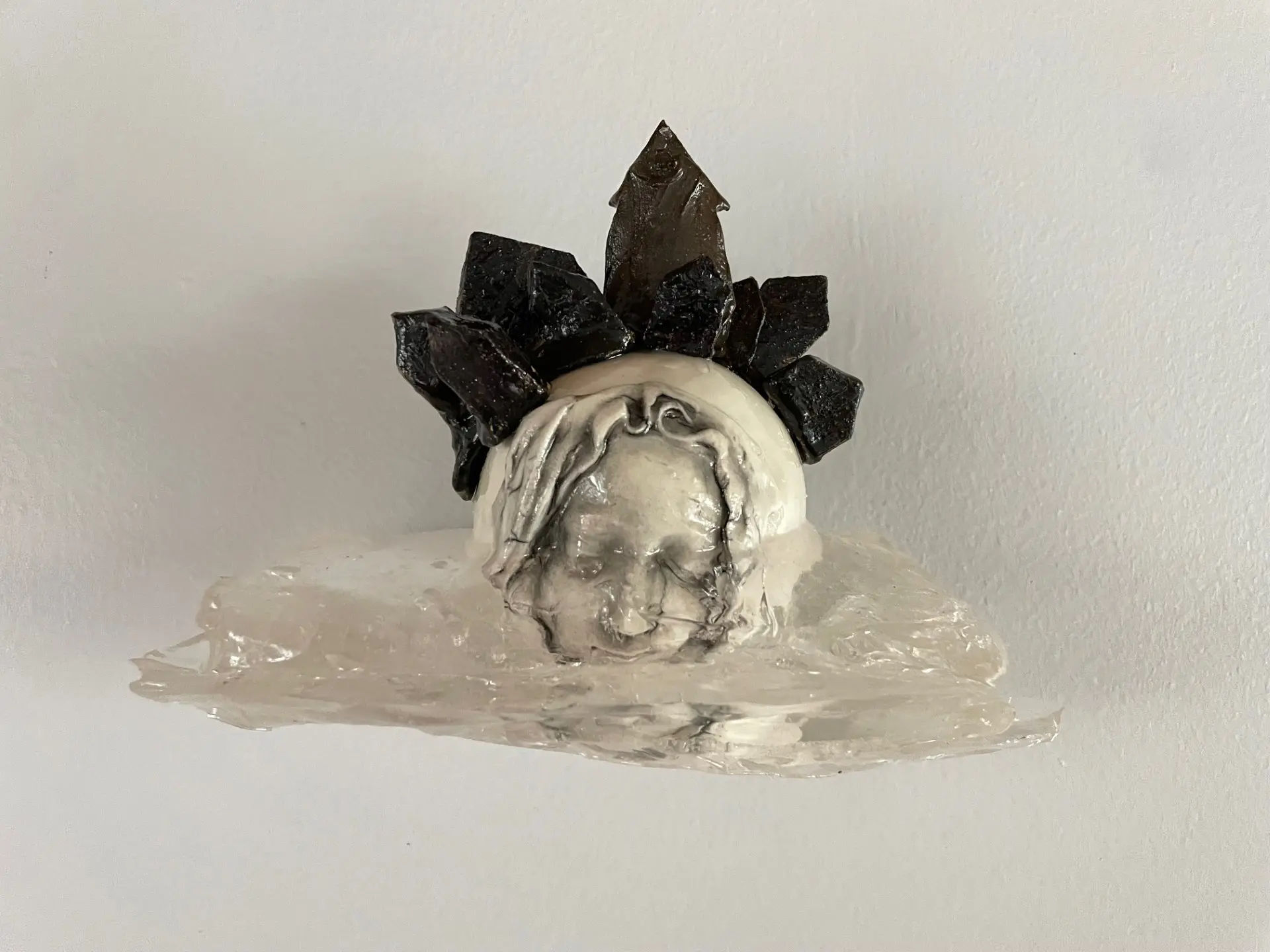 Mixed media sculpture of female face crowed with small houses.